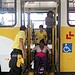 Cadeirante é auxiliada por agentes, na descida de ônibus