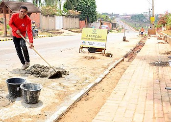 Estudantes caminham por calçada em construção na periferia