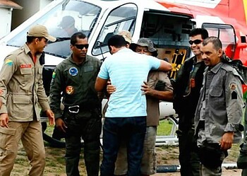 Sobrevivente abraça o filho diante de homens do esquadrão aéreo da PM