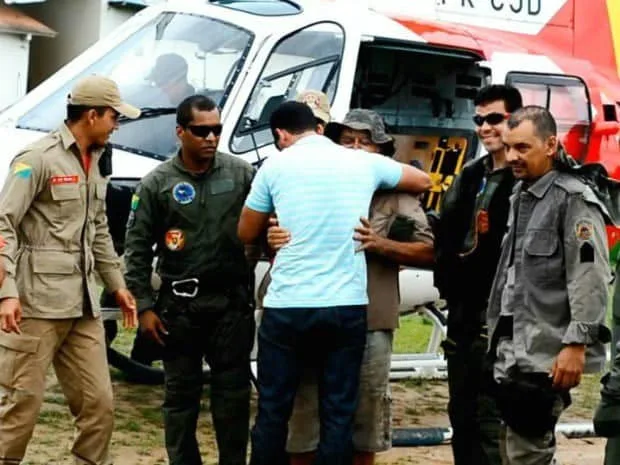 Sobrevivente abraça o filho diante de homens do esquadrão aéreo da PM