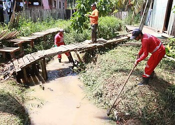 Homens trabalham na retirada de mato e entulho