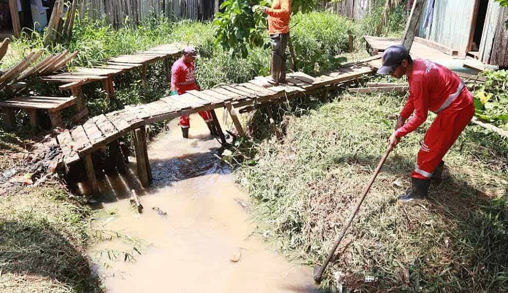 Homens trabalham na retirada de mato e entulho