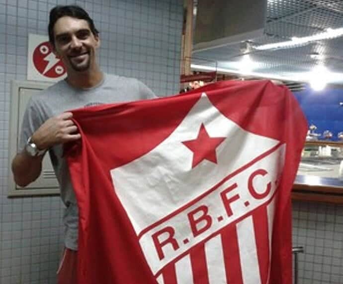 No aeroporto de Rio Branco, o ex-jogador de vôlei Giba tira foto com a bandeira do Rio Branco
