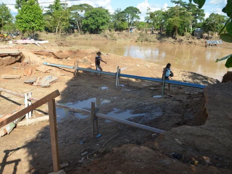 Para ter acesso a outra parte da cidade, moradores passam por dentro do rompimento causado pelo rio. (Foto: Aline Nascimento G1)